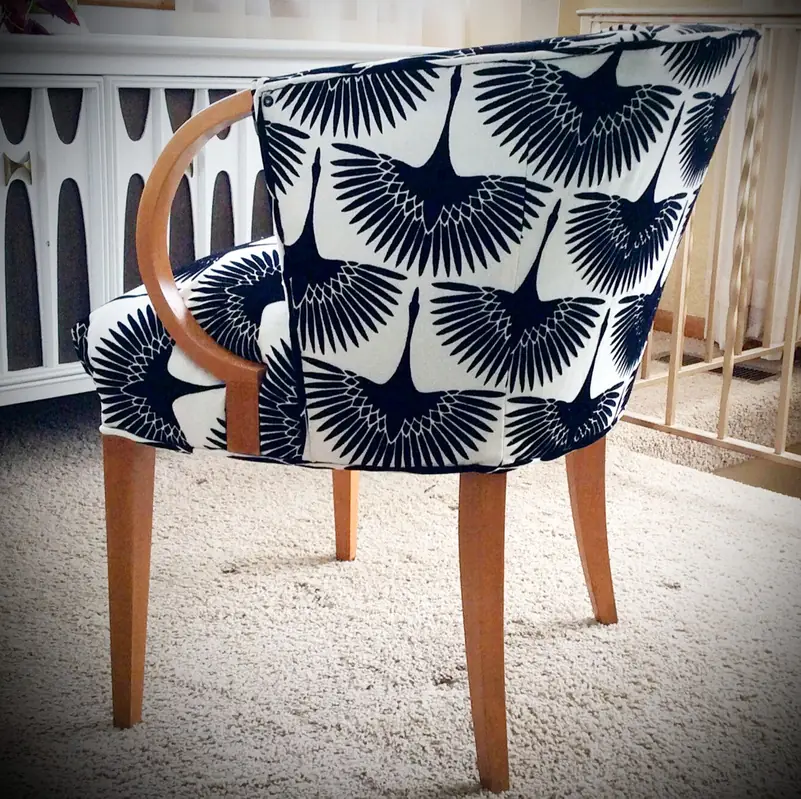 Barrel-back accent chair covered in a navy and white crane print, on a cream rug
